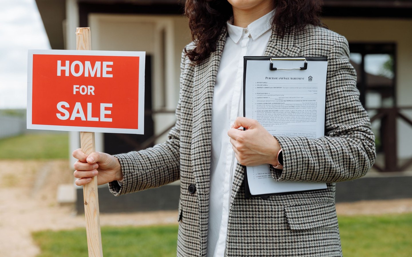 Estate agent holding a for-sale sign outside a property